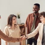 Networking Strategies. Group of young professionals gathered shaking hands.