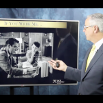 Man presenting in front of TV.
