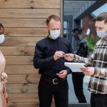 3 people in masks in front of a house