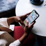 Why Social Media is Crucial for Branding in Luxury Real Estate. Individual holding phone while sitting at a table.